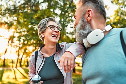 a woman leans on a man’s arm as they share a smile after learning about Medicare basics from Gate City Investment Services