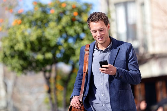 happy professional man walks and enjoys strong bank security while looking at phone