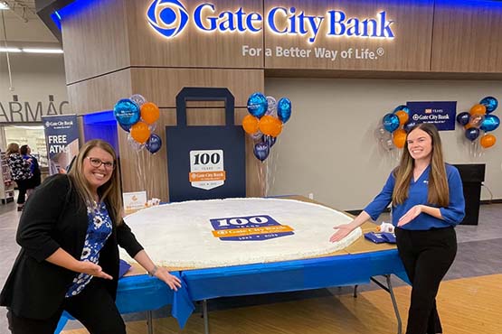 Two female team members gladly present a 100-pound cookie during Gate City Bank’s ribbon-cutting ceremony in Elk River, MN