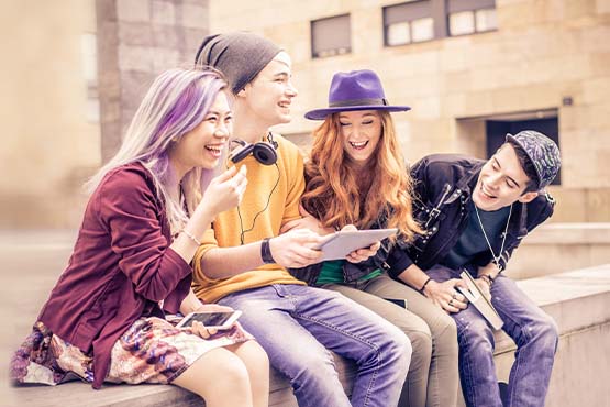 four happy young adults sit outside after setting up student banking at Gate City Bank