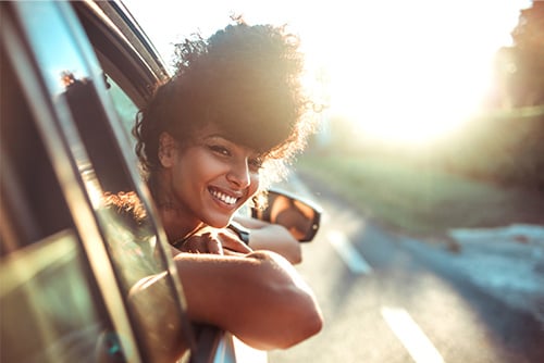 young woman smiling and leaning out the window of her new car, purchased with a Gate City Bank auto loan in Fargo, ND