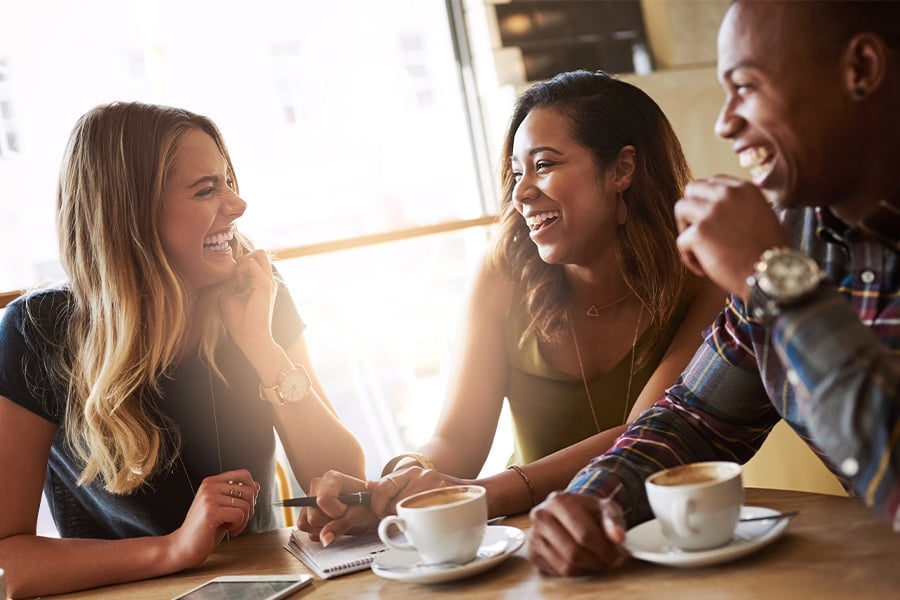 Three young friends in a coffee shop, earning Gate City Bank debit card reward points on their latte purchases