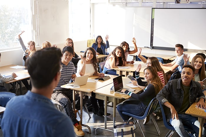 eager students in a classroom raise their hands to ask questions about financial literacy