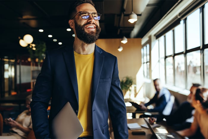 happy man with sportcoat and glasses looks on after securing business real estate loans