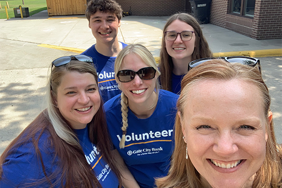 Becky Mindeman and fellow Gate City Bank team members from Grand Forks, ND, smile for a selfie in front of St. Joseph’s Social Services