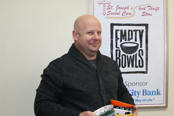 Mickey Munson holds multiple bowls in his hands in front of a wall hanging that says Empty Bowls, sponsored by Gate City Bank</p>
<h2>A Fork in the Road.