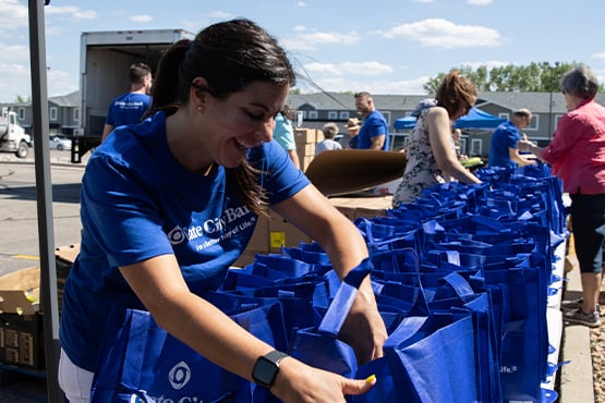 happy Gate City Bank team member volunteers on sunny day by sorting bank’s blue bags