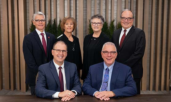 Gate City Bank's six board members gather next to a conference room table and smile at the camera