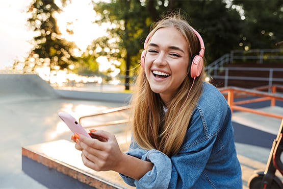 happy woman enjoys no overdrafts while using pink phone and headphones