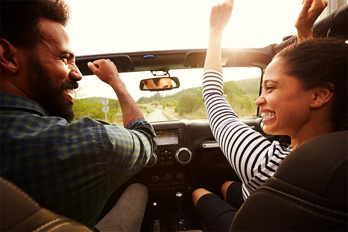man and woman glance at each other and share a laugh as they drive ahead