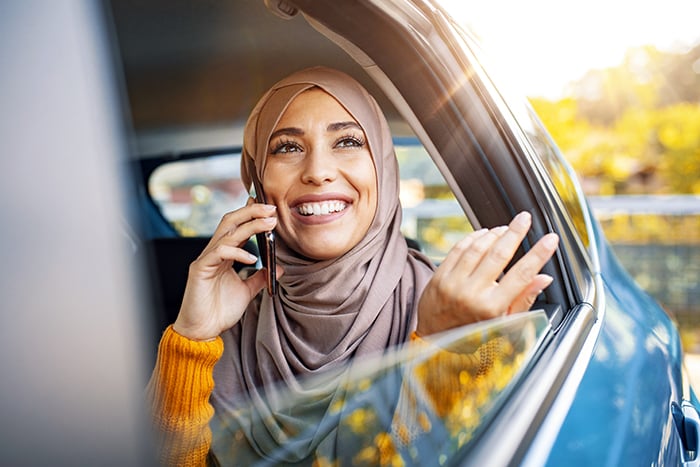 happy young woman talks on phone from car backseat while enjoying line of credit