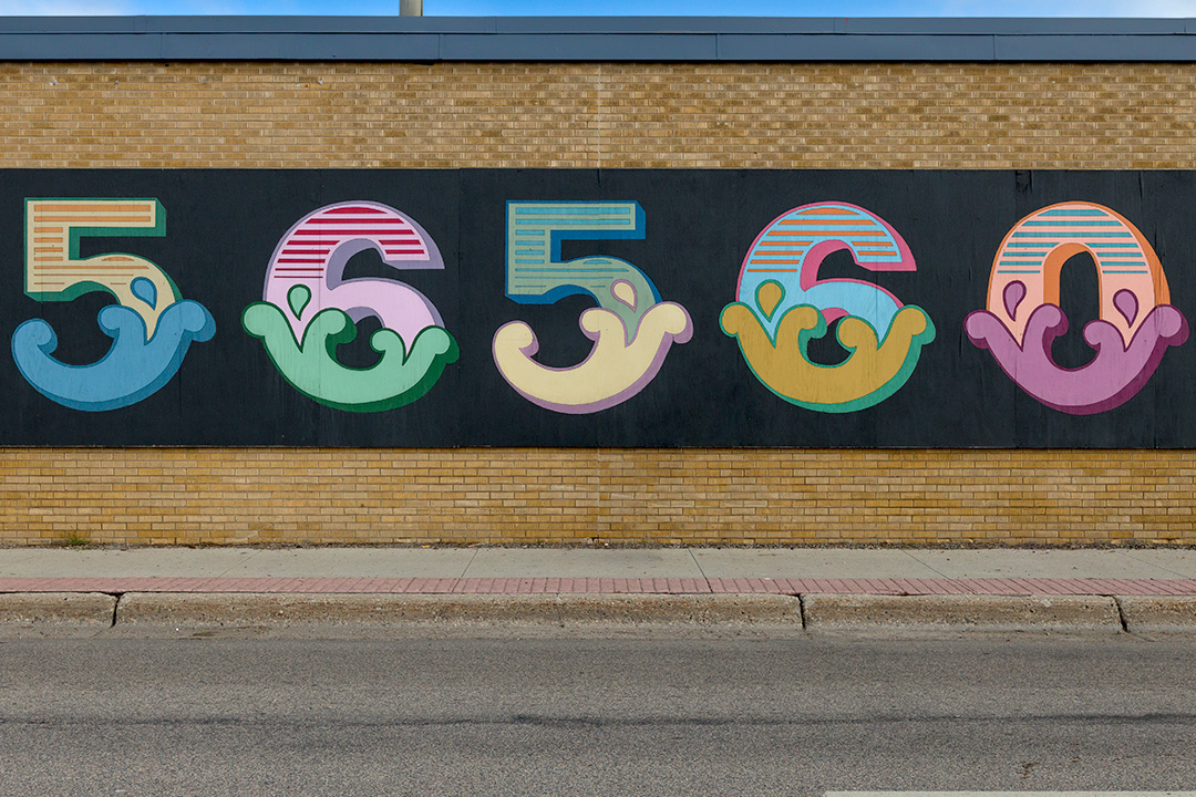 Close-up of hand-painted, brightly colored 56560 mural on a brick wall located on 6th Street South in Moorhead, MN