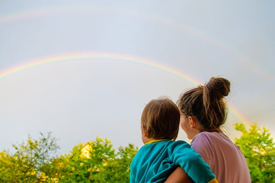 mother and young child looking at a rainbow after preparedly weathering a big storm