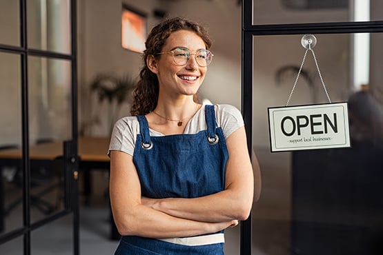 smiling young lady stands in front of her store after reading helpful article on business banking basics from gate city bank