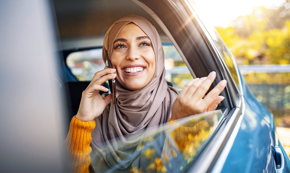 happy young woman talks on phone from car backseat while enjoying line of credit