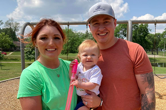 Bleau Hoge, his wife, Phoenix, and their baby daughter, Ember, smile for the camera while visiting the park on a sunny day