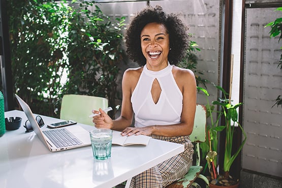 laughing woman uses laptop on a sunny day outdoors to protect herself against fraud with gate city bank tips