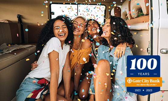 four happy young female friends huddle together surrounded by confetti and Gate City Bank's 100 year logo