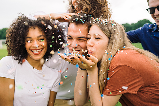 group of friends laughs and blows confetti to celebrate the awards that gate city bank has received through the years