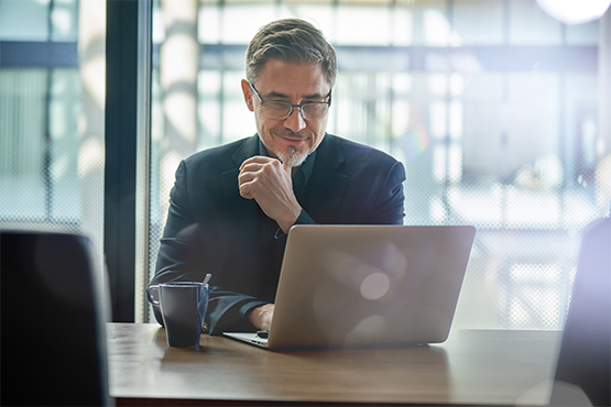 male business owner at desk with coffee and laptop reviewing his relationship CD with gate city bank