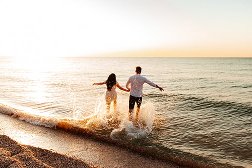 Couple walking on a beach after winning a vacation just by using their Gate City Bank debit card through mobile wallet