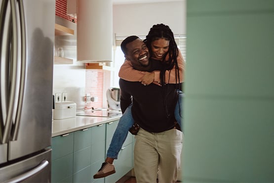 Newlywed couple laughing in the stylish retro kitchen of their first home in St. Cloud