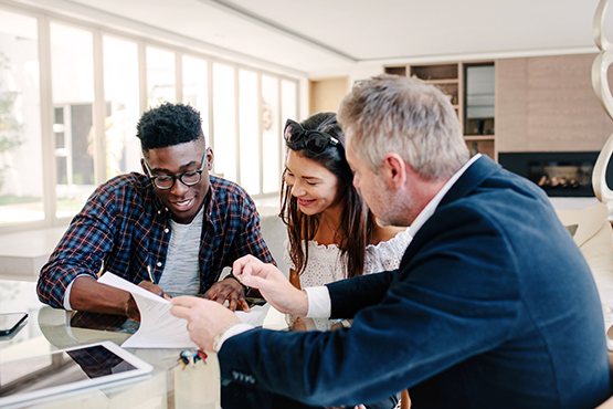 smiling Gen Z couple taking a moment to review paperwork and closing documents at the bank with their mortgage lender