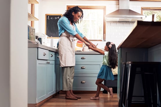 mom and daughter dancing on the hardwood floor of their remodeled kitchen, thanks to a Gate City Bank home equity loan 