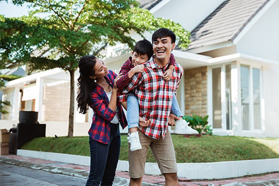 joyful young family of three walks in front of their home after refinancing their mortgage with Gate City Bank
