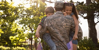 military dad carries children in backyard after buying new home using va loan with gate city bank