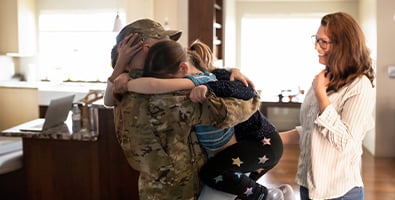 military dad hugs children in their new home purchased with a va loan from gate city bank