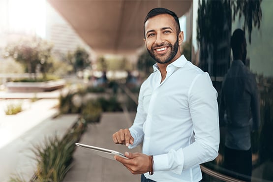 happy male entrepreneur holds laptop outside and enjoys his business savings account