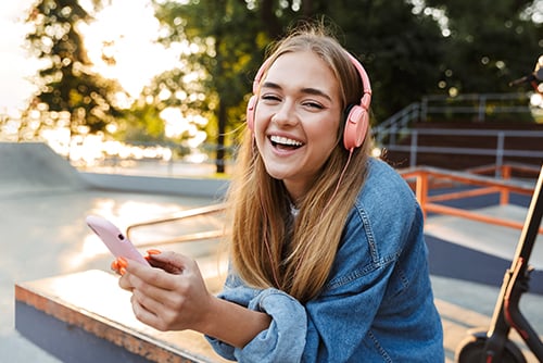 happy woman enjoys overdraft protection while using pink phone and headphones