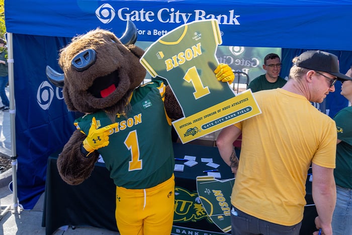 Thundar, NDSU’s mascot, shows off a jersey-shaped yard sign at Gate City Bank’s Bison Homecoming party in downtown Fargo.