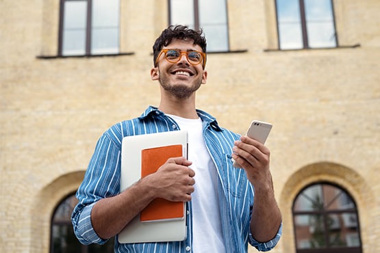 a happy man holding a laptop and smartphone looks on after learning how to build credit fast with 5 tips from Gate City Bank