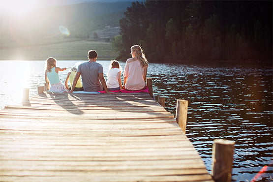 happy young family sits at end of dock on lake after securing their MinnStart Home Loan