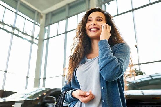 A young woman smiles while preparing to buy a new a car, happy with her decision to finance through a bank loan in Fargo, ND