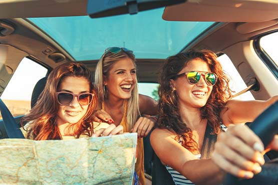 three excited women in sunglasses sitting in a new car, embarking on a road trip thanks to Gate City Bank personal loans