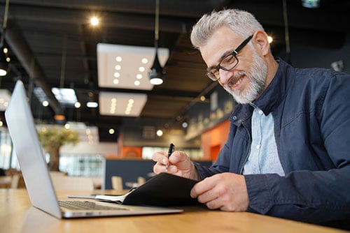 Small business owner smiling while using online banking for his business in downtown Fargo, ND