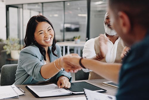 relaxed and happy young woman shaking hands with her local insurance advisor in Fargo, ND