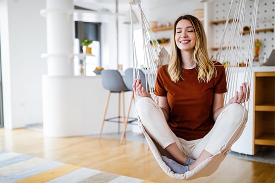 happy and relaxed woman meditating in her living room