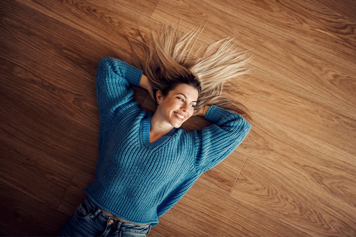Young woman relaxing on her hardwood floor in Fargo, ND, imagining her next home project with a home equity loan