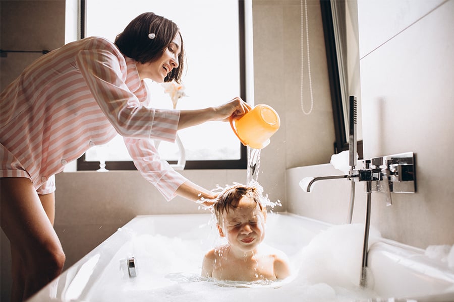 Mom laughing and pouring water over her son in their new soaker tub, thanks to a Gate City Bank home improvement loan 