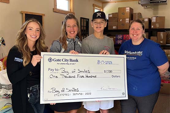 Two Gate City Bank team members in Elk River, MN, deliver a $1,500 big check to local nonprofit, Bag of Smiles