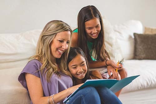 mom and two young girls happily look at folder after securing a student savings account