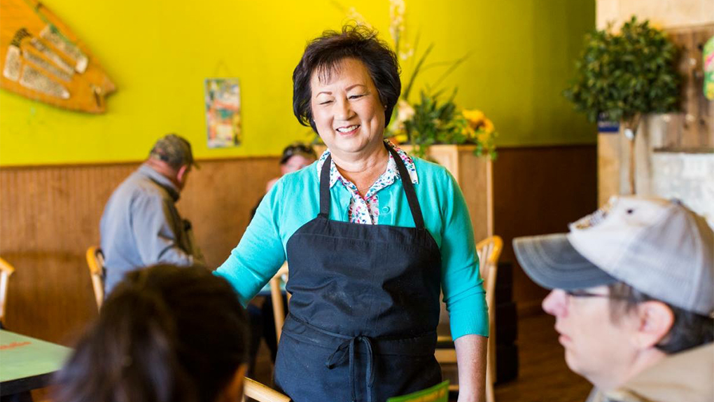 Hula’s Fire Grill owner Sandy Wong smiles while talking with customers