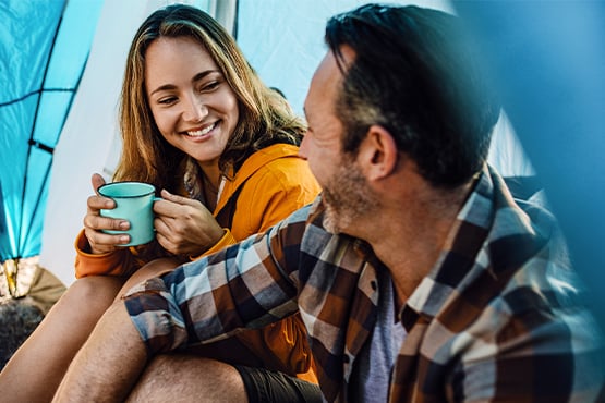 Millennial couple smiling over coffee while camping together in central Minnesota