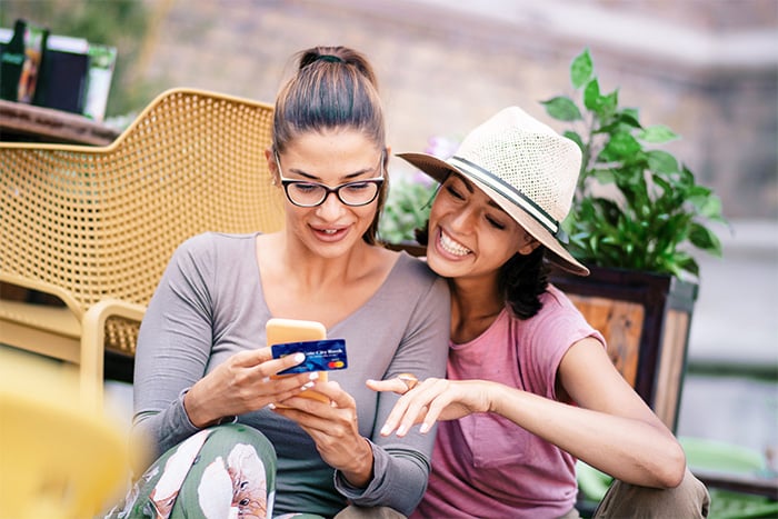 Two young women ordering a new Gate City Bank custom debit card while looking at design options together on mobile