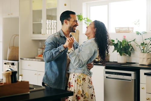 A young couple dances in their Fergus Falls, MN, kitchen after applying for the Mortgage Rate Relief program