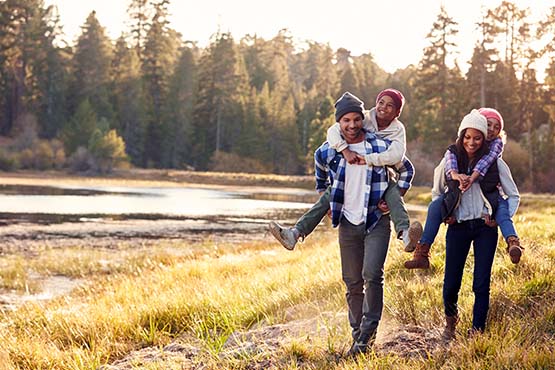 Family of four in stocking hats, walking along Wall Lake in autumn outside Fergus Falls, Minnesota